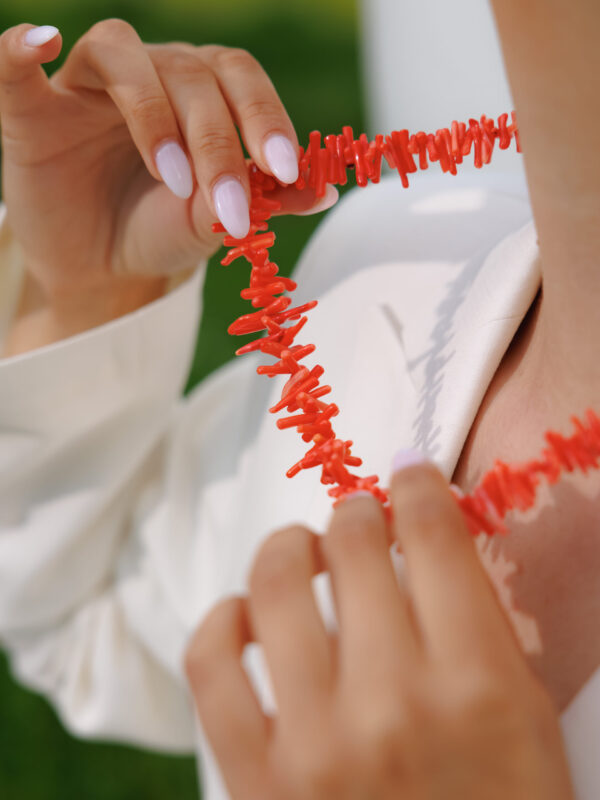 Hands holding a coral and pearl necklace