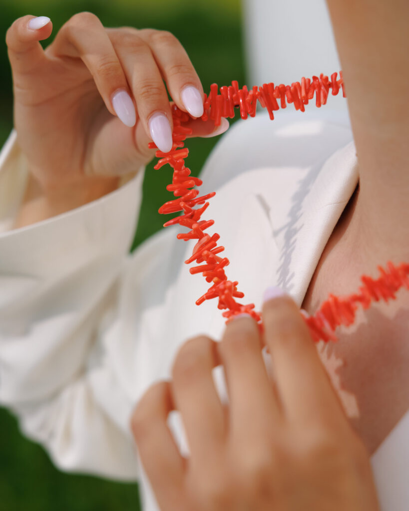 Hands holding a coral and pearl necklace
